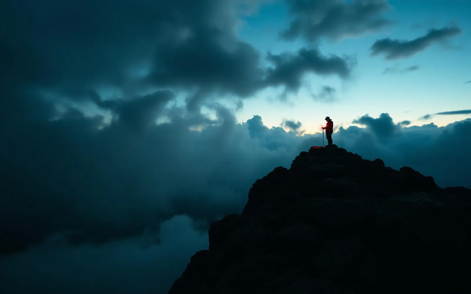 Solo hiker on a stormy ridge at dusk
